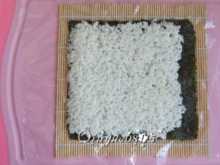 基础寿司,寿司帘上铺一张保鲜膜，放紫菜，把米饭铺匀。紫菜其中一端留出一点空边（此图片是为说明保鲜膜等用法）。