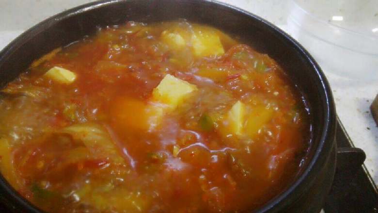 辣白菜豆腐汤,将汤倒入石锅，将汤汁煮至沸腾时，倒入豆腐块。