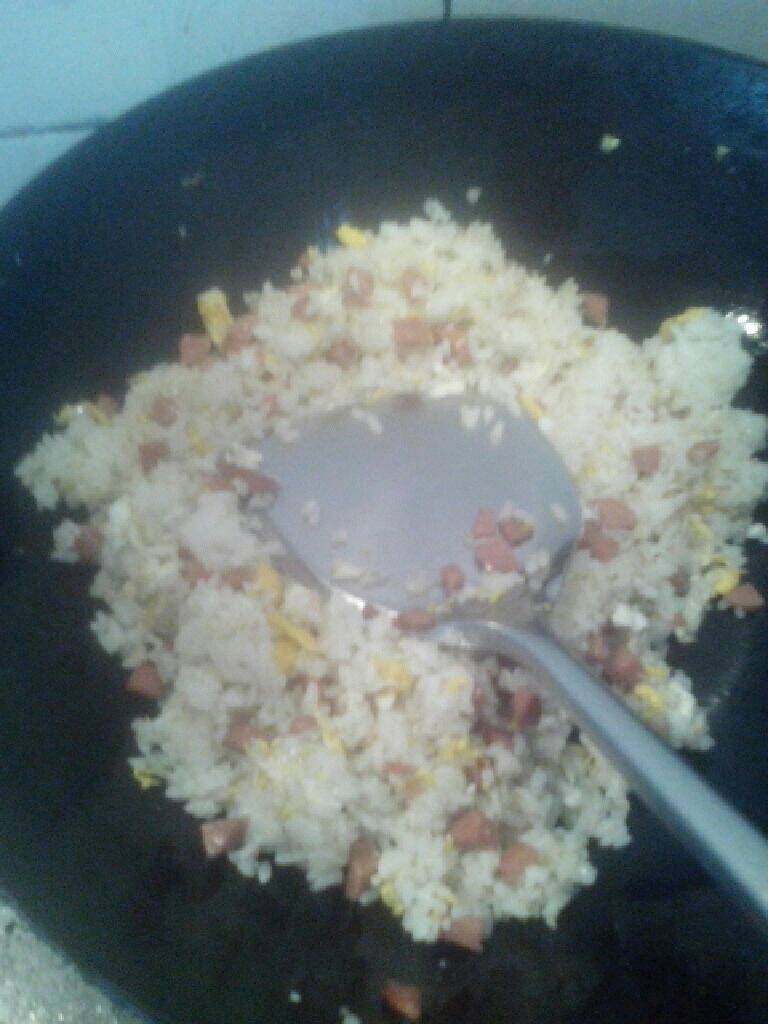 火腿蛋炒饭,一面翻一面用铲子按，把米饭块按碎