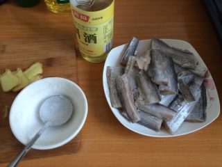干烧带鱼,如图把姜切成片状，放入处理干净的带鱼中然后再放入盐和料酒搅拌，姜和料酒可以去除腥味