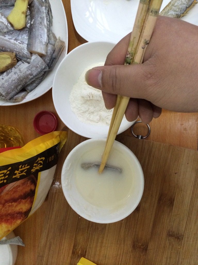 干烧带鱼,如图裹粉时，一碗加水调稀，一碗干粉。先把鱼放入稀释的粉中裹上一层粉液然后再放入干粉碗中裹上一层干粉，这样油炸时不会粘锅