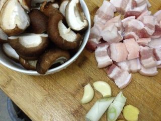 香菇红烧肉,五花肉洗净切块 宽厚2厘米的样子 香菇去蒂洗净对半切开 葱切段 姜两片 蒜头两个