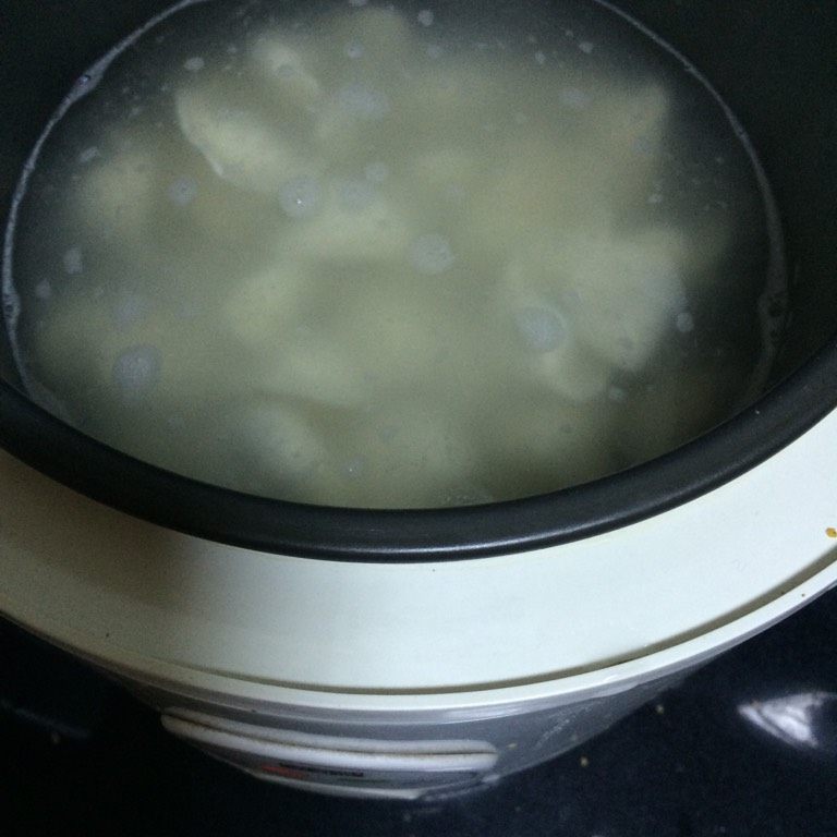 电饭锅煮饺子,如图用勺子推锅底，贴着锅边推，防止饺子粘锅