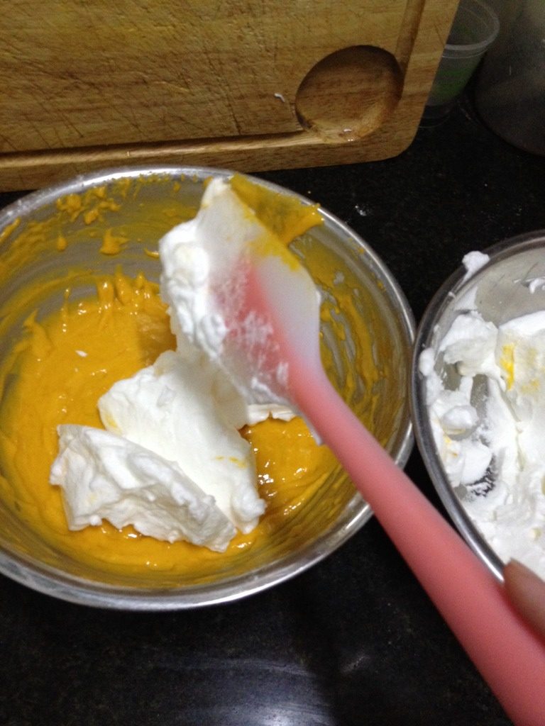 南瓜红枣小蛋糕,勺三分一打发好的蛋清至蛋黄糊了，用搅拌刀从底部往上翻的切拌方式搅拌均匀后倒回至原来剩下的蛋清盆内，继续用同样的方式拌匀。