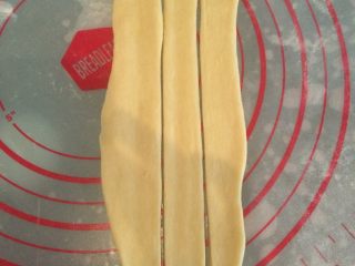 葱香培根辫子面包,如图取一个剂子，擀成长圆形，中间切3刀；
