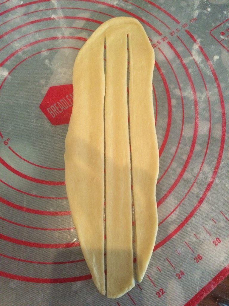 葱香培根辫子面包,如图取一个剂子，擀成长圆形，中间切3刀；