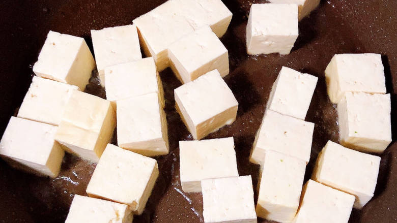 白果炖豆腐,锅中倒入油，加热至五成热，放入豆腐慢煎。