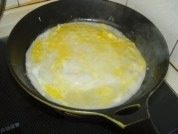 鸡蛋油条卷饼,打入一个鸡蛋，用筷子将膜挑破，鸡蛋均匀摸到面饼上。
