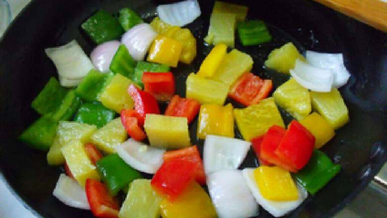 美味的菠萝古老肉,锅里放三分之一汤匙食用油，炒一下彩椒和洋葱片，炒均匀。