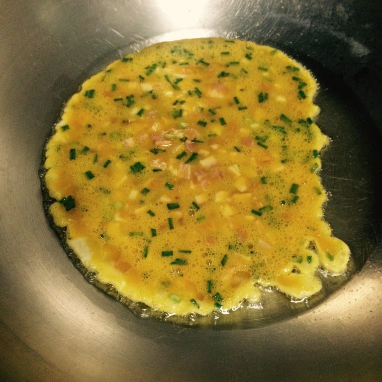培根虾仁炒蛋,如图起油锅，至5分热下培根蛋液，表面略有凝固后翻炒，全部凝固后盛起备用；