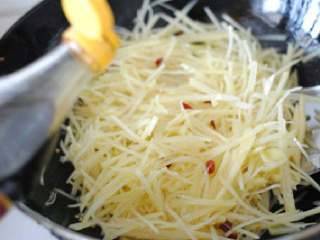 酸辣土豆丝,煸炒一小会后倒入适量醋继续翻炒土豆丝。