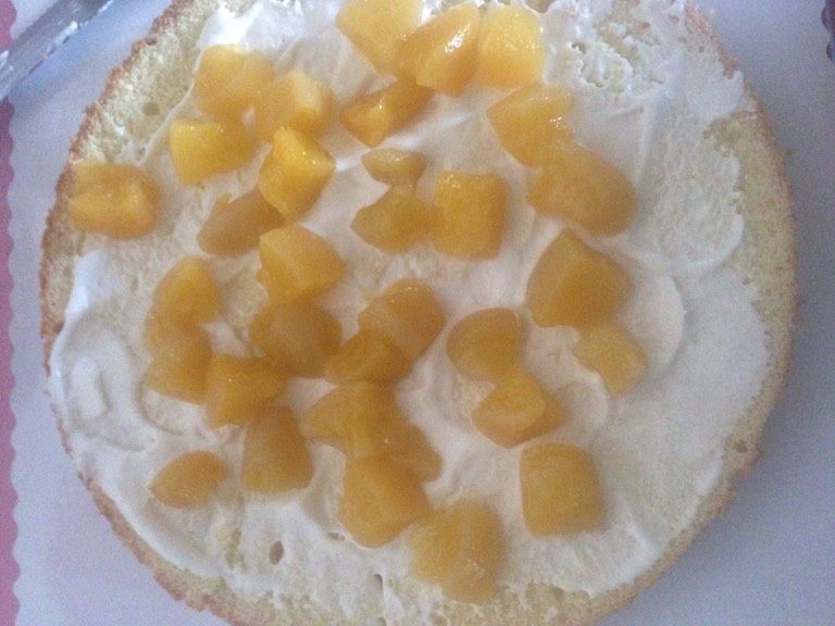 水果生日蛋糕,取一片蛋糕片，涂抹奶油，加入水果夹心，黄桃的哦