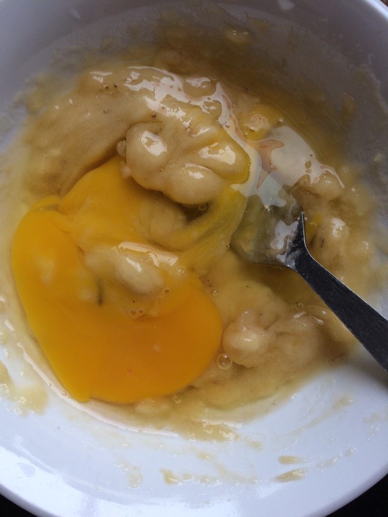 软煎香蕉饼,如图在香蕉泥中打一个全蛋，加入牛奶搅拌均匀