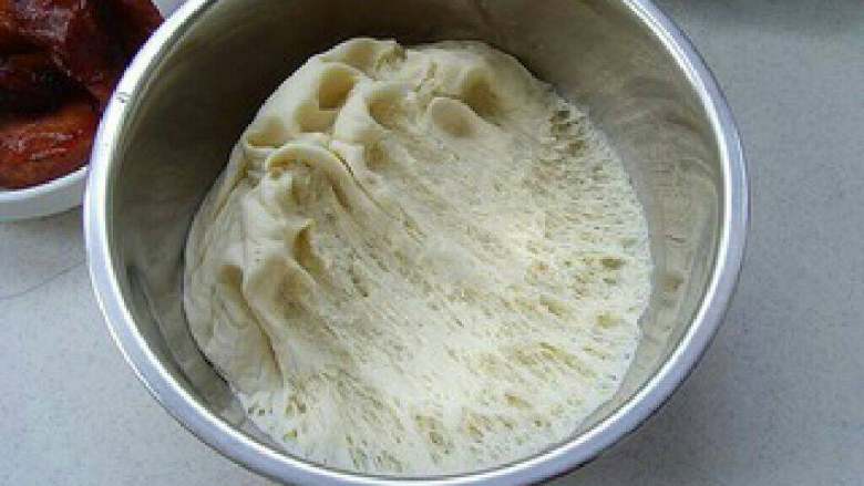 美味的叉烧包,包上保鲜膜发酵至原来的1.5倍到2倍大，呈现蜂窝状；用手轻轻将面团挤压排除气泡。