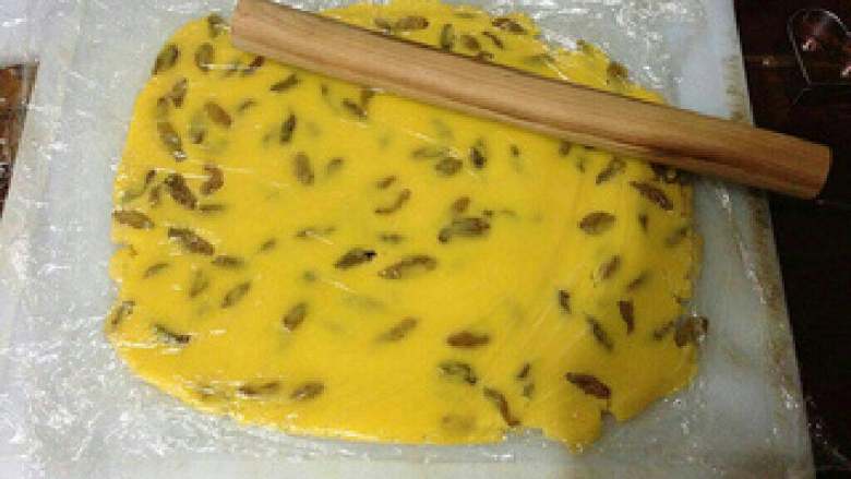 葡萄干蛋黄奶酥,把面团放在案板上，先用手压扁，再用擀面杖擀成约1厘米厚的面片。