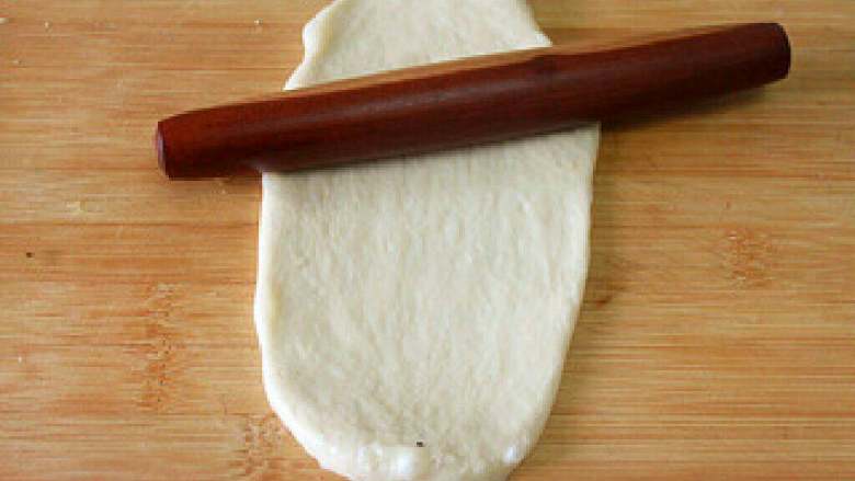 【简易版热狗】,把发酵好的面团压平，擀成椭圆形面片。