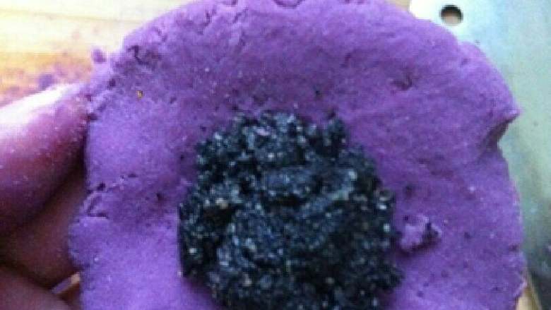 紫薯芝麻球～情人节礼物,把紫薯面团压扁，摊平放手心，放入黑芝麻馅，包起来搓圆。