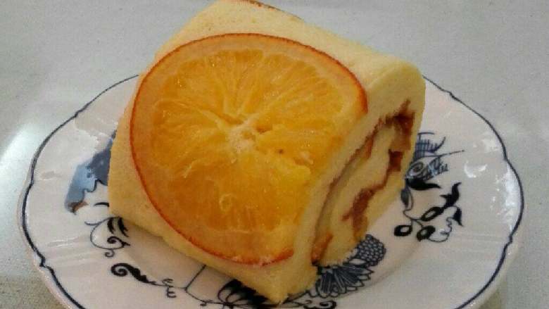 香橙蛋糕卷,将有橙子的一面放在新油纸上，将橙子果酱抹在蛋糕上，从一边向另一边卷起，固定1小时后去油纸切片即可。
