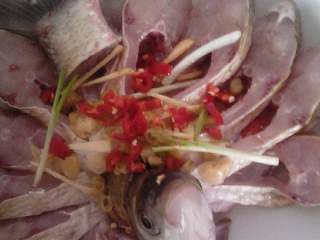 孔雀开屏鱼,放上切碎的泡椒和红椒，摆上姜丝和葱段。