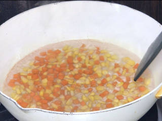 玉米虾仁蛋炒饭,起锅烧开水，放入红萝卜和玉米粒，拌匀，煮至断生，捞出备用