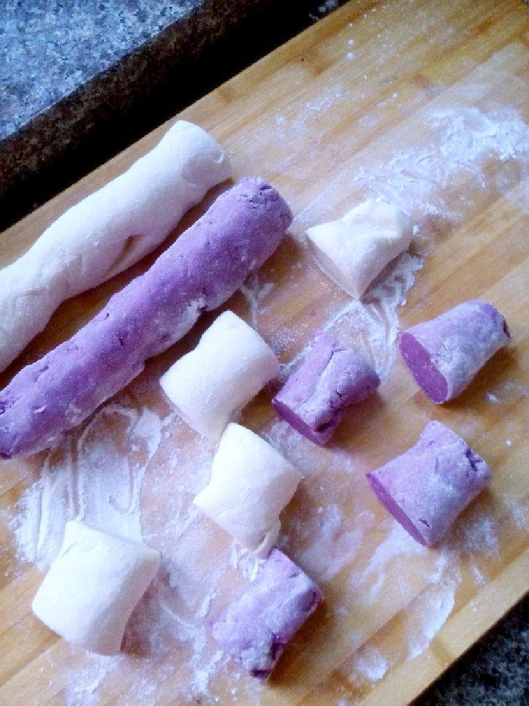 开花紫薯馒头,将发好的两个面团，多揉几次，排尽里面的空气。揉成长条，切成小段。