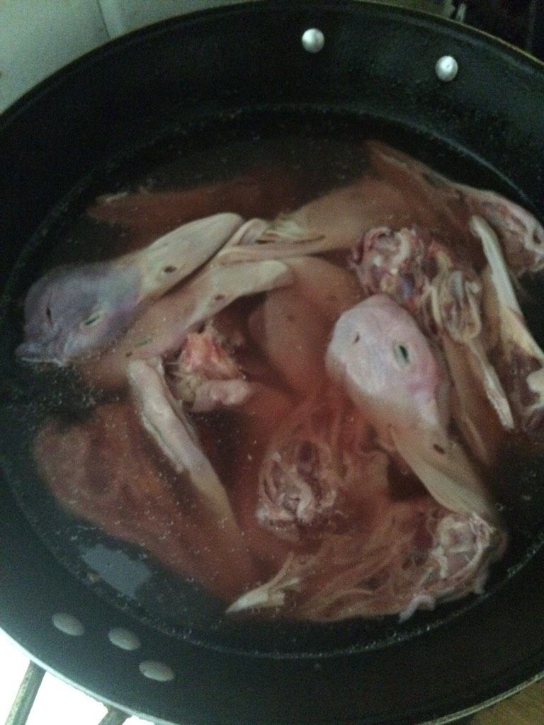 卤鸭头,如图，在鸭头初步解冻后，即每个鸭头可以分开后，放入冷水锅里小火，加入一勺盐去血水，这个水不能烧开，看到锅里有血水出现就差不多了