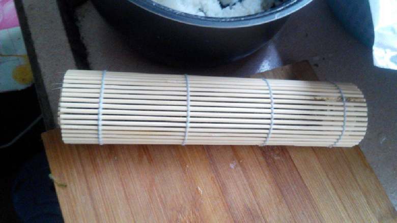 食寿司卷——剩米饭的华丽转身,顺势用竹帘将紫菜卷起；卷起后，用手紧握一分钟后打开