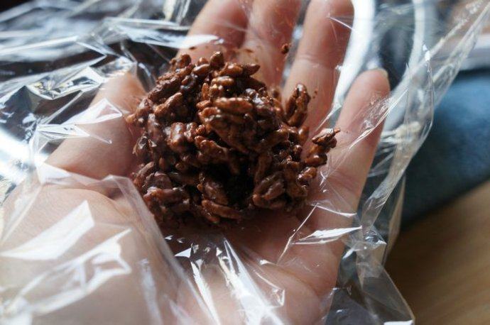 巧克力杏仁脆香米,取一小张保鲜膜放在手上，取适量的巧克力杏仁脆香米放在保鲜膜上。然后扭转保鲜膜，就和包糖果一样，把巧克力杏仁脆香米，包成圆球状！