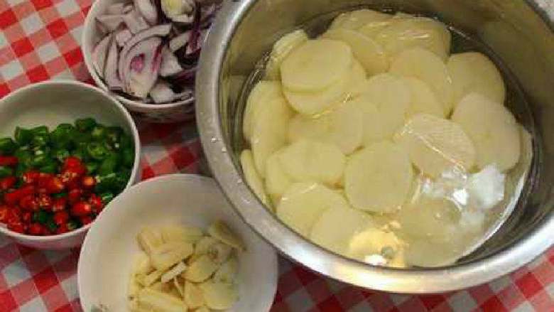 干锅土豆片,土豆切片后过水清除表面的淀粉、洋葱切块、青红辣椒切段、蒜切片。