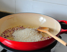  意式牛肝菌炖饭,下入大米，转小火，慢慢煸炒2、3分钟，至米粒均匀吸透油脂