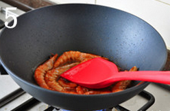 茄汁油焖大虾,待一面煎至变色后翻面，并挤压虾头，压出红油