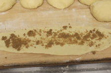 红糖皇冠面包,将面团擀成椭圆长形，放上红糖卷成团，切半放置烤盘中