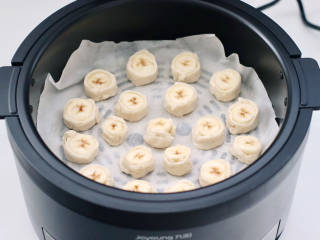 快手香蕉酥,空气炸锅提前预热后，炸篮铺上油纸，码上香蕉块。