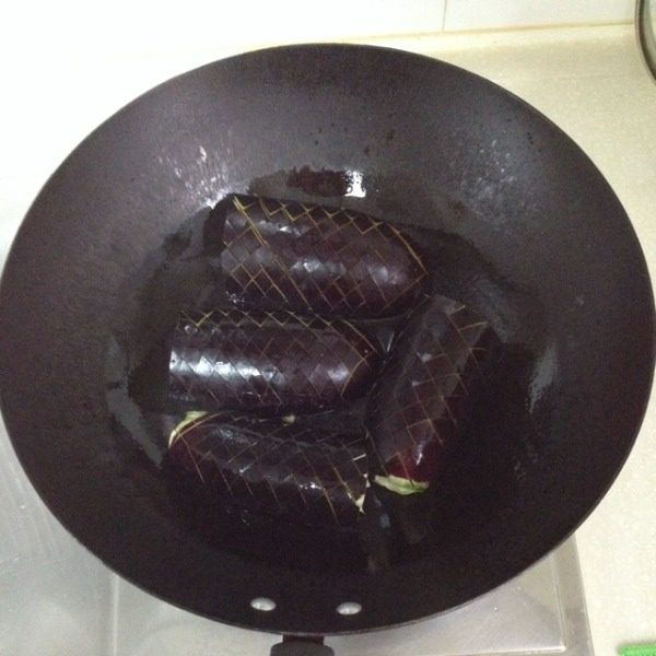 妈妈风味茄子,准备工作完成后就开始煎茄子了。油锅里的油放得要比平时炒菜多一些，油稍热就可以把茄子放进，先煎瓤那一面。