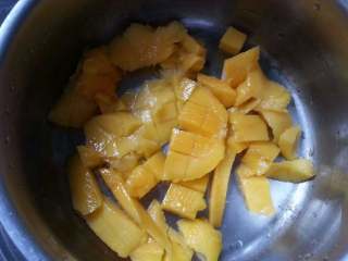 芒果酱,将一半果肉倒入小锅中、开微火煮。