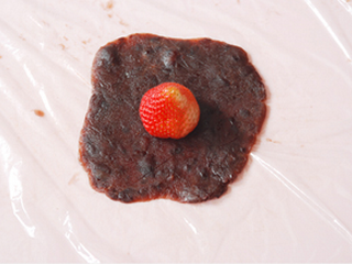 草莓大福,豆沙馅挤在保鲜膜上，盖着保鲜膜压扁（也以用一次性手套），中间摆入一颗草莓
