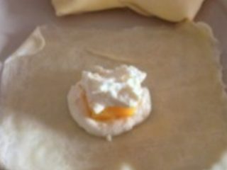 芒果班戟,如图：
取一张面饼，在中心铺上一层奶油糊，再放一块芒果条，再铺上一层奶油糊。