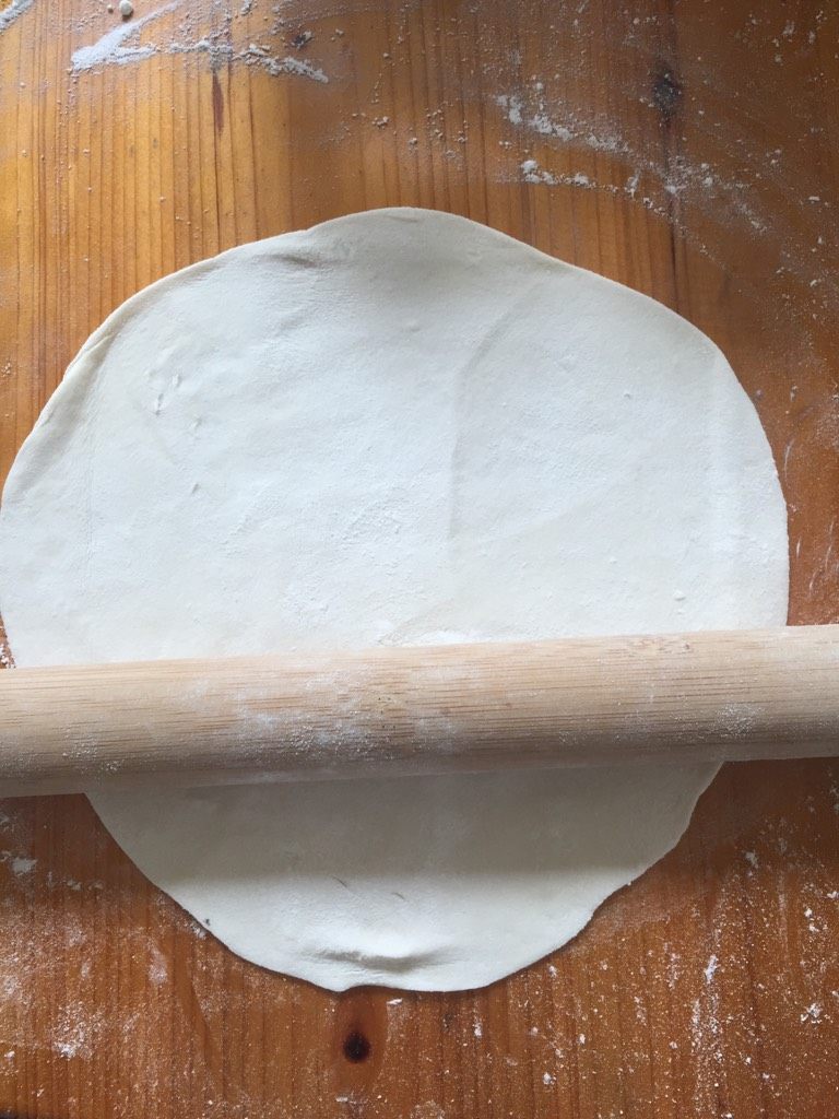 手擀面条,把面团揉成一个圆，然后用擀面杖擀成饼状，这时候在撒上面粉，继续擀，擀到差不多薄