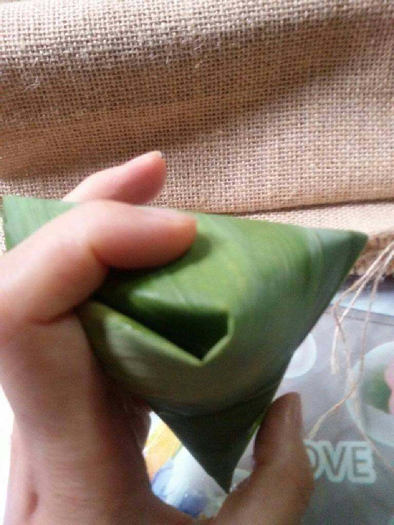 蜜枣什锦粽子,把多余的粽叶顺着折叠，包裹成三角形。