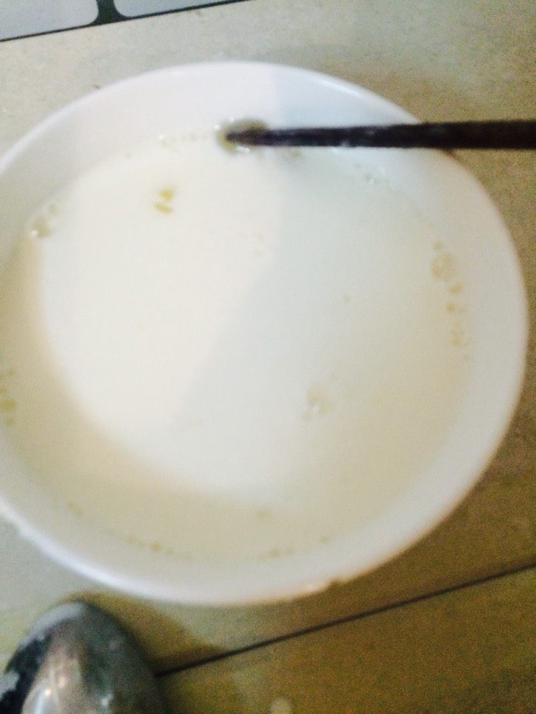 双皮奶,用勺子将奶皮掀开，把牛奶倒入蛋清内搅拌均匀，留少量牛奶在碗里防止奶皮粘碗底