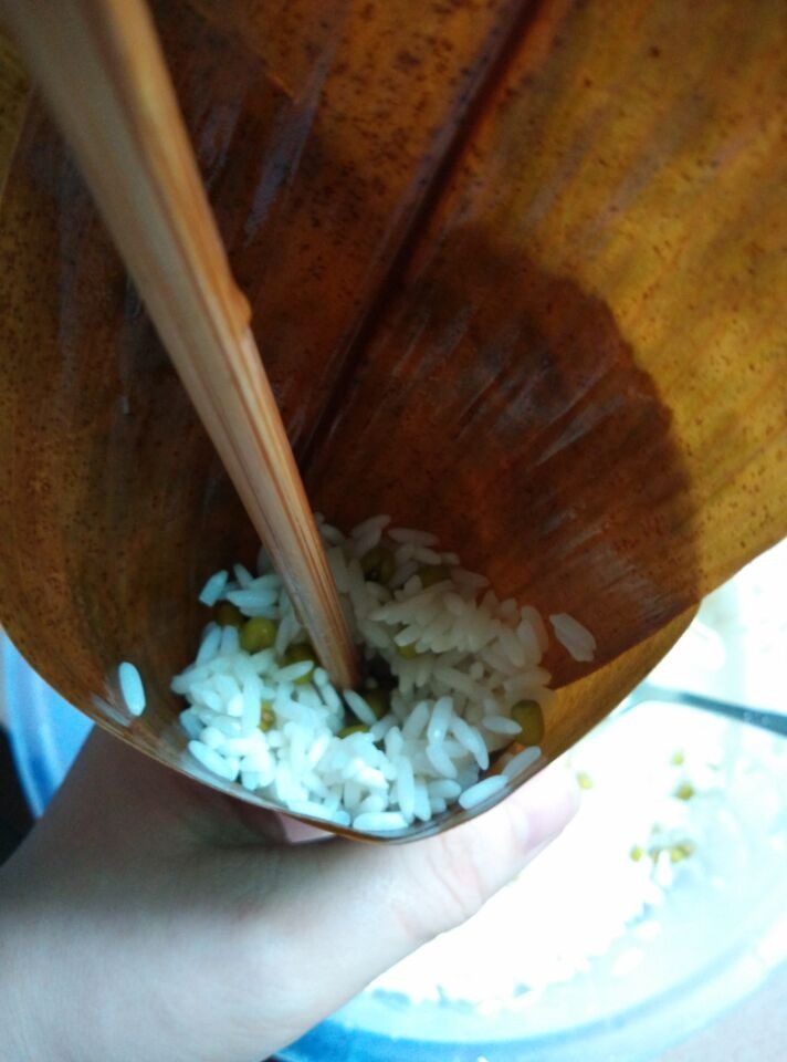 碱水粽,如图将竹叶卷好放入拌好的糯米用筷子撮紧包好