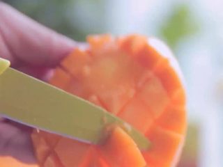 水果冰块冷饮,芒果切片后，用刀在果肉上横向纵向划花，在从中间顶出，就可以轻松的将芒果丁取出啦！