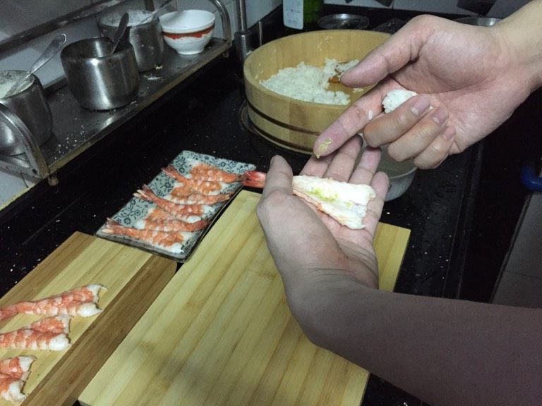 鲜虾手握寿司,在虾里面涂上芥末。