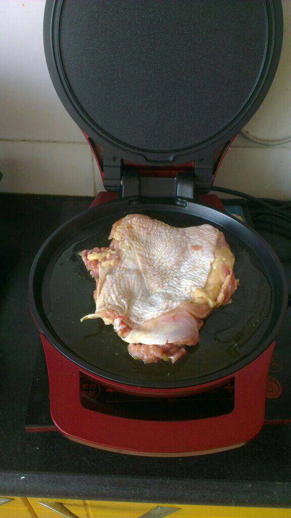 香煎鸡腿,电饼档内刷一层油，放入腌好的鸡腿肉盖上锅盖煎至一面金黄；