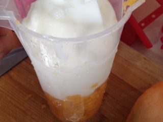 酸奶芒果冰淇淋,将切好的芒果丁放入量杯中，再倒入酸奶，搅拌均匀