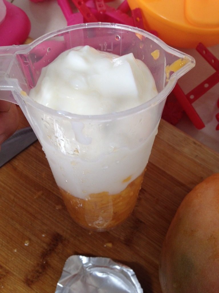 酸奶芒果冰淇淋,将切好的芒果丁放入量杯中，再倒入酸奶，搅拌均匀