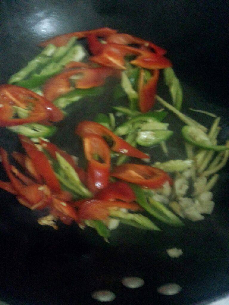 双椒炒鱿鱼,锅加油烧热把姜，蒜，青椒，红椒一起放入爆炒一下