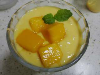 芒果酸奶昔,放入几块切好的芒果果肉，用一根薄荷叶作装饰。