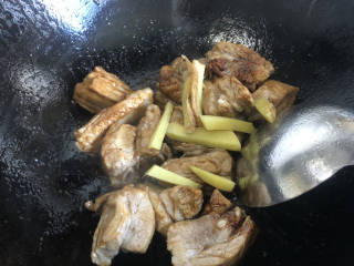 白萝卜炖猪肉,倒入排骨翻炒，把排骨炒香，加入姜丝和料酒继续翻炒。