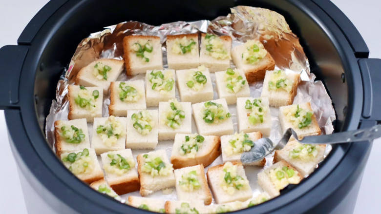 蒜香芝麻吐司酥,用小勺把葱蒜黄油铺在吐司块上。